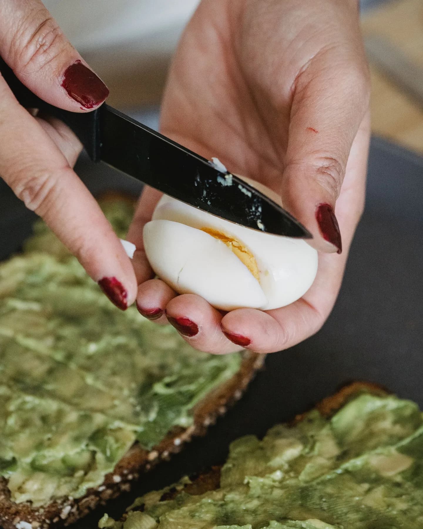 Ženske ruke seckaju kuvano jaje za avokado tost.