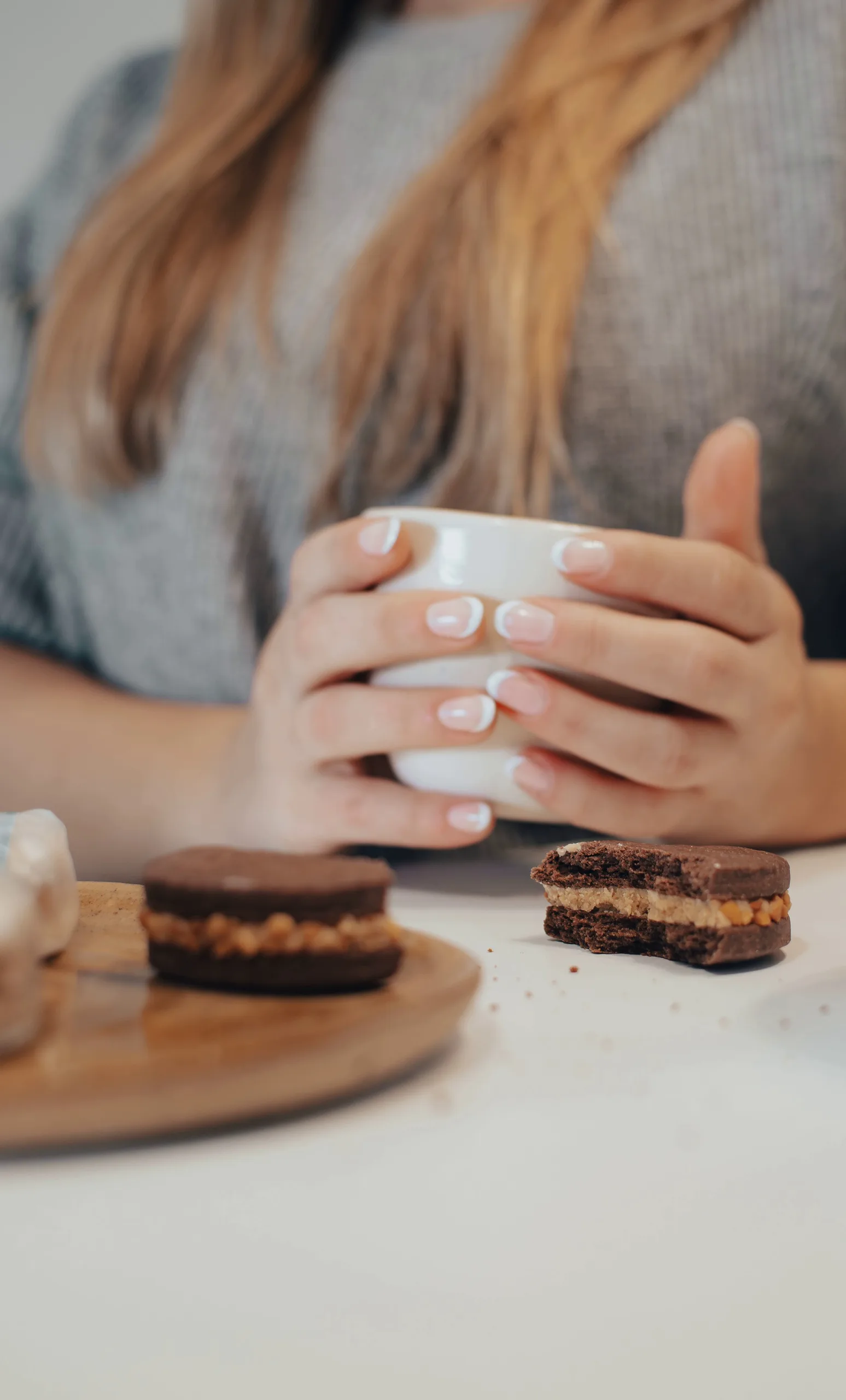 Žena drži šolju kafe uz čokoladne bezglutenske kolačiće