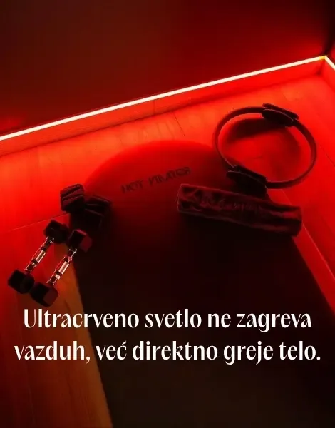Crna prostirka, tegovi i pilates obruč na drvenom podu pod crvenim osvetljenjem