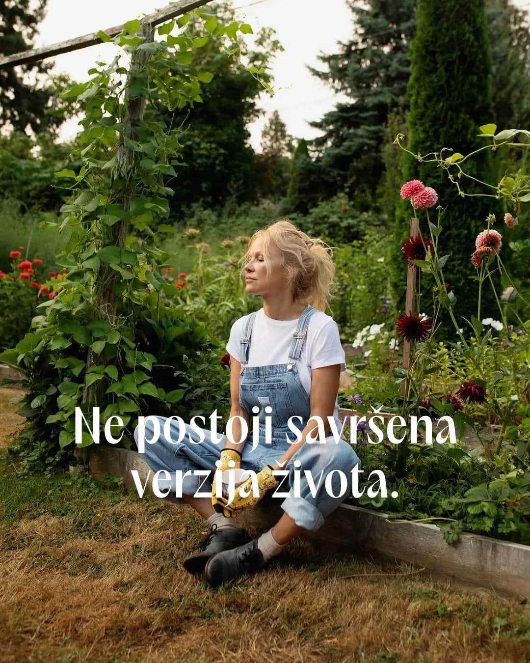 Žena u teksas kombinezonu sedi u bašti cveća uz natpis Ne postoji savršena verzija života