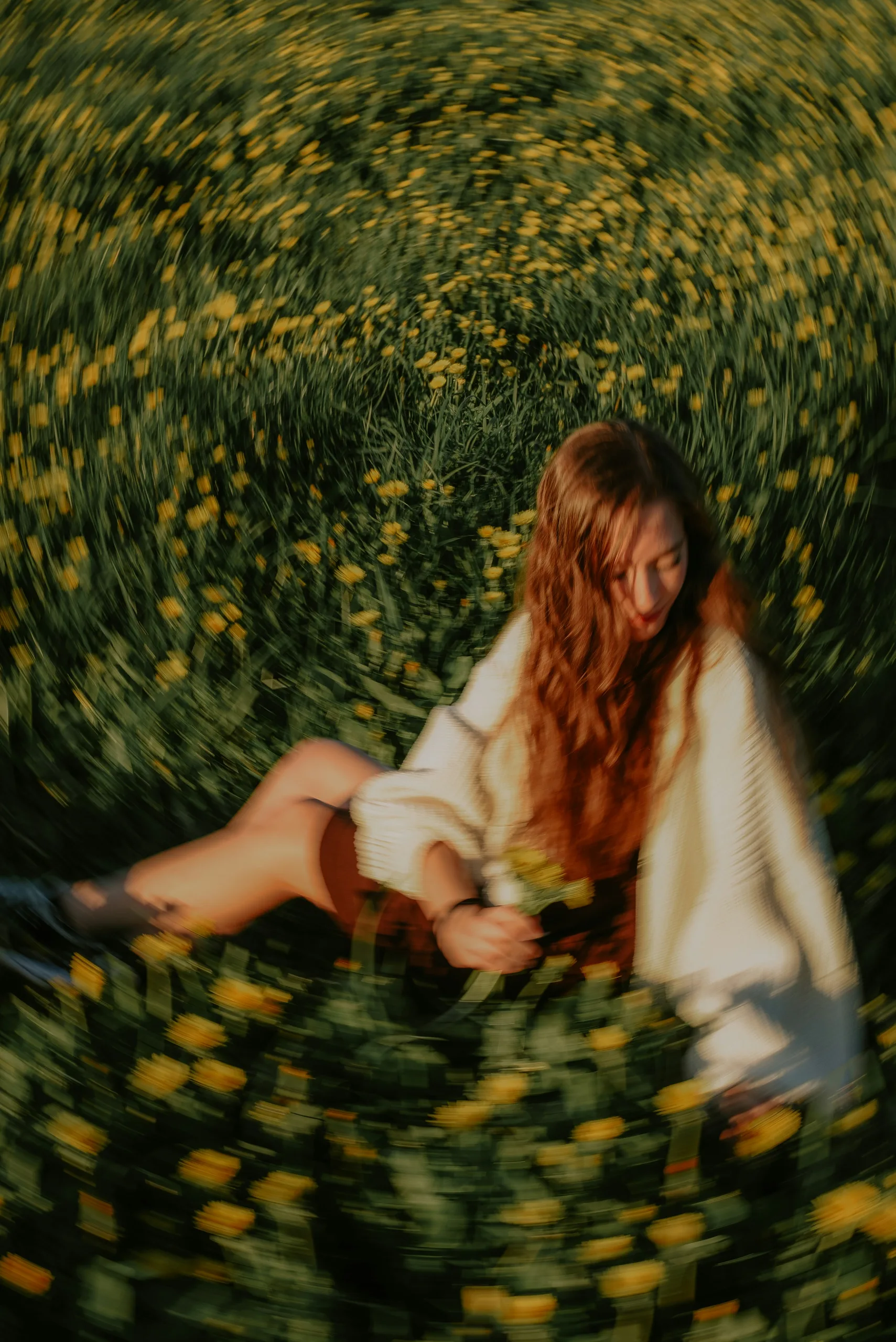 A woman with long wavy hair sitting in a field of yellow dandelions with a swirling blur effect.
