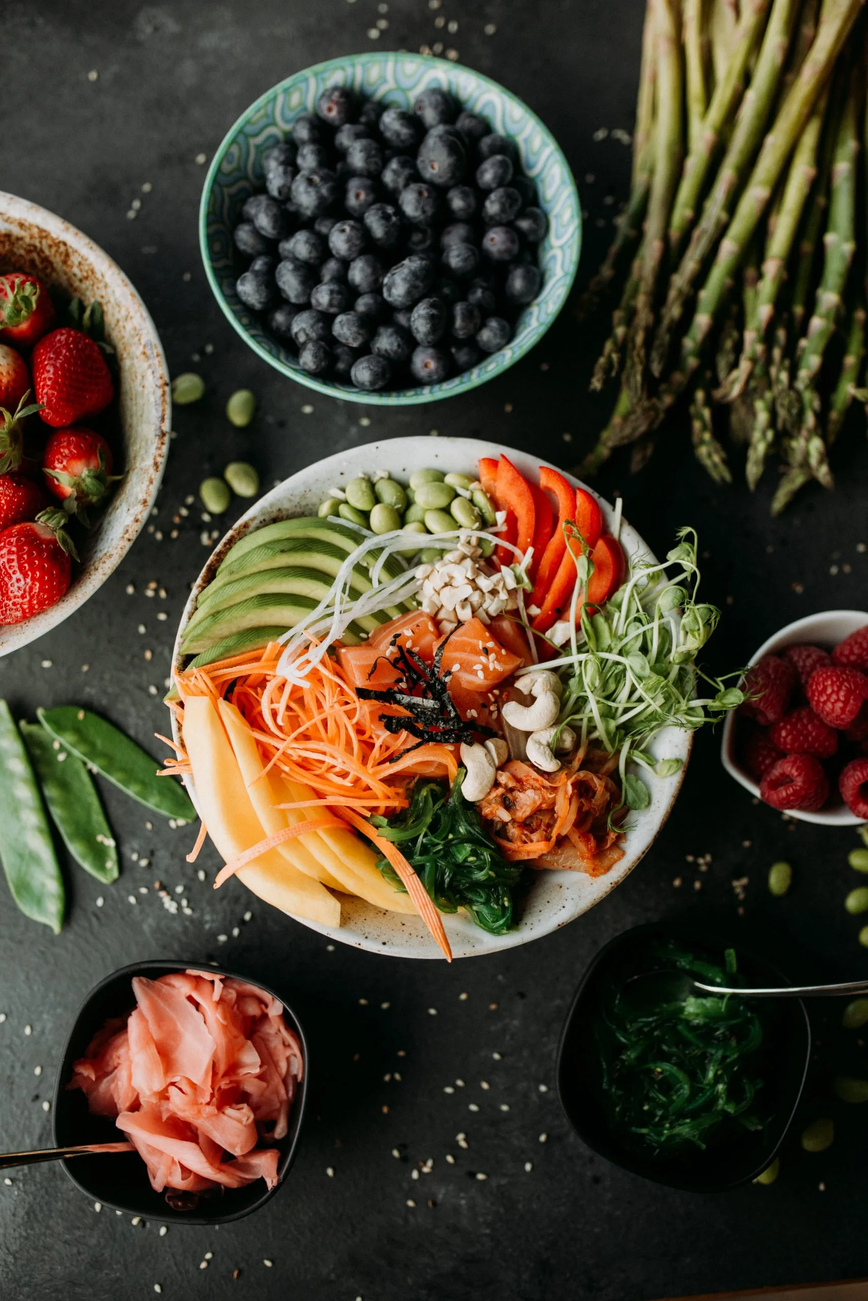 Top-down view of a poke bowl with diced salmon, sliced avocado, mango, shredded carrots, bell peppers, and microgreens.